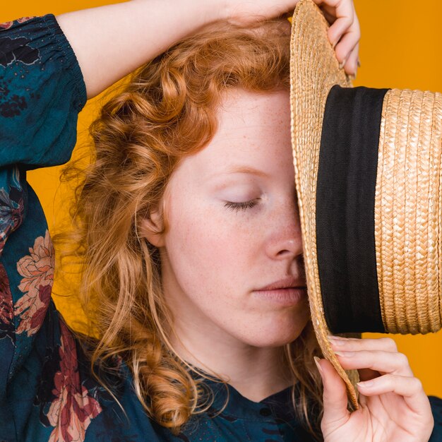 Presentación femenina bonita joven con la cara de la cubierta del sombrero