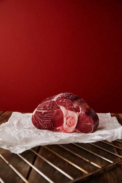 Foto gratuita presentación de filete de pierna angus en pared roja de mesa de madera