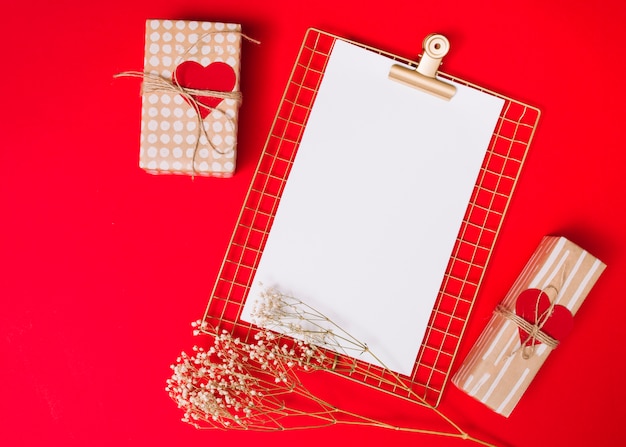 Foto gratuita presentar cajas con adornos de corazones y portapapeles cerca de la planta.