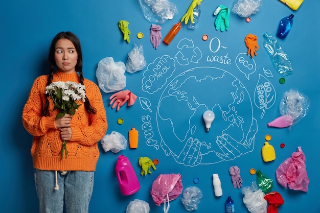 El preservador de la naturaleza decepcionado triste se encuentra con un ramo contra un fondo azul con un planeta dibujado y una burbuja de luz en el centro, piensa en salvar al mundo de la contaminación.