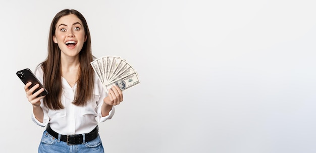 Foto gratuita préstamos de microcrédito en línea y concepto bancario mujer feliz sosteniendo teléfono móvil y dinero sonriendo y