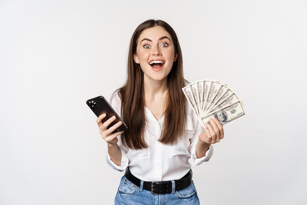 Préstamos de microcrédito en línea y concepto bancario mujer feliz sosteniendo teléfono móvil y dinero sonriendo y...