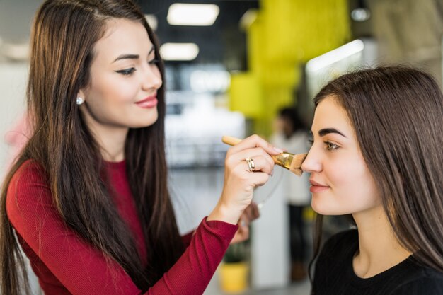 Pretty Master está haciendo un maquillaje natural para una bella modelo en un salón de belleza