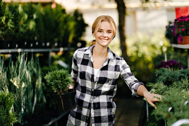 Pretty Woman en ropa linda alcanzando plantas en invernadero