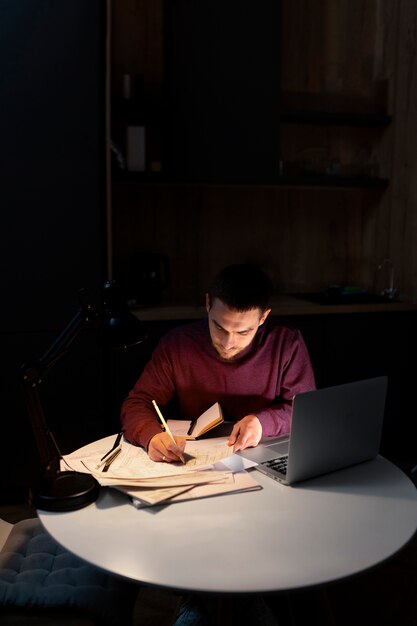 Pria dengan bidikan sedang bekerja larut malam di laptop