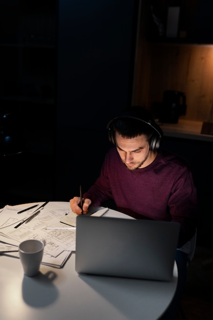 Pria dengan bidikan sedang bekerja larut malam di laptop