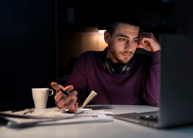 Pria dengan bidikan sedang bekerja larut malam di laptop
