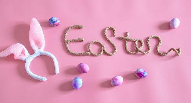 Foto gratuita primavera pascua festivo inscripción creativa de pascua en rosa con elementos de decoración de pascua.