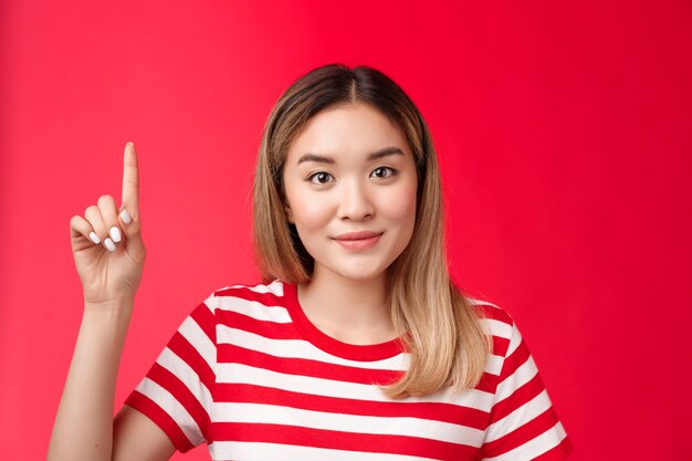 Primer amistoso optimista linda mujer asiática con peinado rubio desgaste verano camiseta a rayas sonriendo ha ...