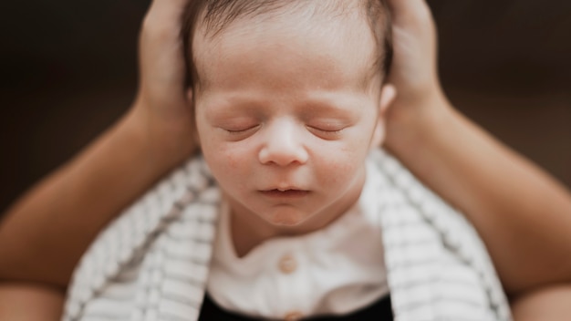 Primer bebé pequeño durmiendo en manos de la madre