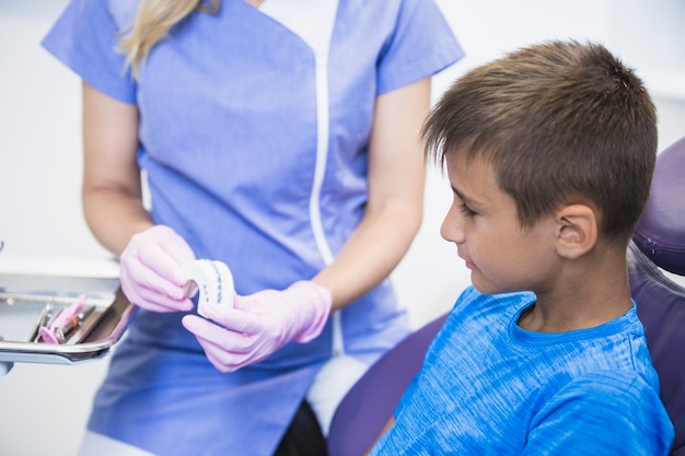 El primer de un dentista de sexo femenino que muestra los dientes moldea el molde al paciente en clínica