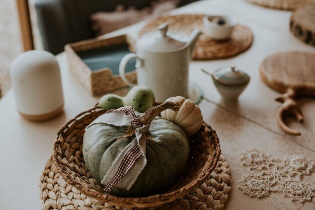 Primer disparo de ángulo alto de una mesa rural con un par de pequeñas calabazas en un plato de paja