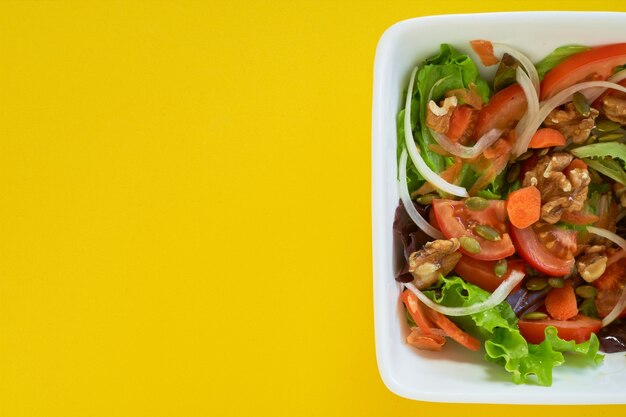 Primer disparo de un plato de ensalada sobre fondo amarillo. Comida vegetariana saludable. Espacio para texto