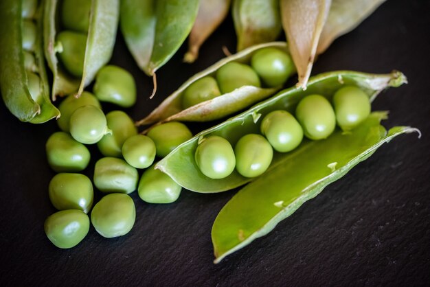 Primer disparo de semillas de guisantes verdes frescas sobre fondo de madera negra