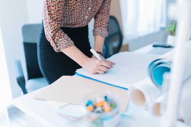 Primer de la escritura de la empresaria en nota adhesiva en oficina