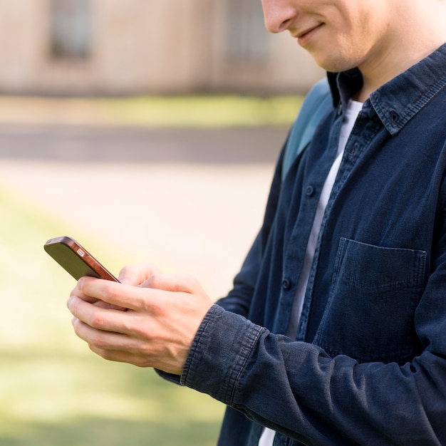 Primer estudiante masculino comprobando el teléfono móvil