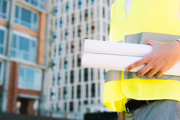 Primer hombre en chaleco de seguridad con planos de construcción