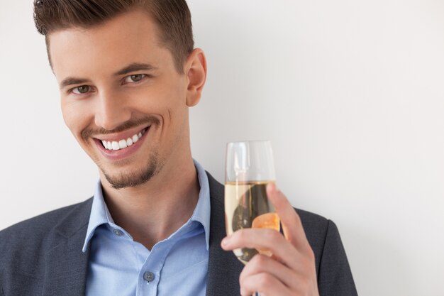 Primer del hombre joven sonriente con vaso de vino