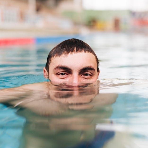Primer hombre en la piscina respirando bajo el agua