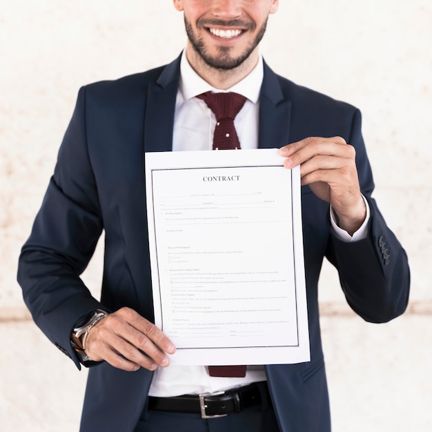 Primer hombre sonriente sosteniendo un contrato