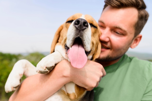 Primer hombre sosteniendo a su adorable perro en el parque