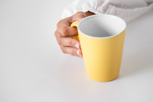 Primer mano que sostiene la taza amarilla