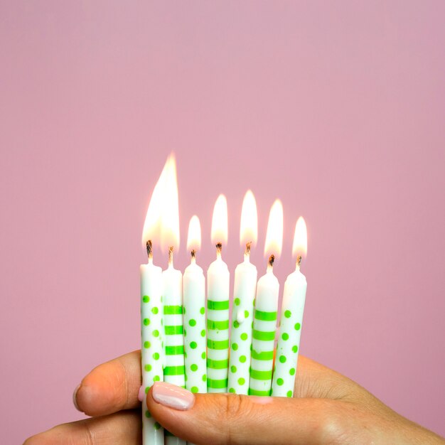 Primer mano sosteniendo pequeñas velas de cumpleaños