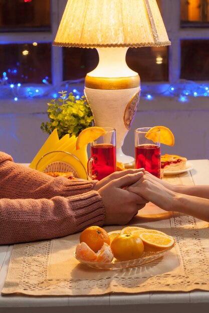 El primer de las manos de la feliz pareja joven con tazas de té y frutas