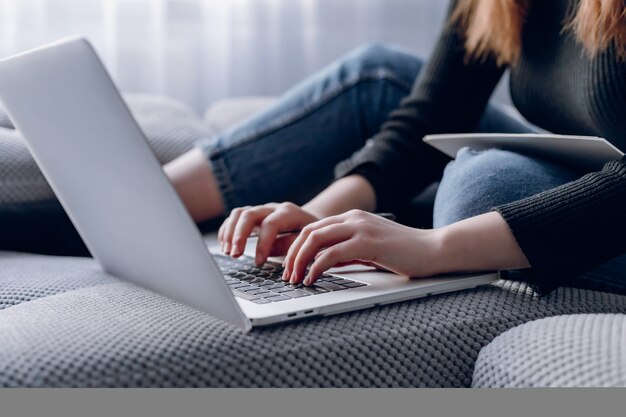 Primer de las manos femeninas que pulsan en la computadora portátil con estilo en interior moderno. trabajar en linea y laptop.