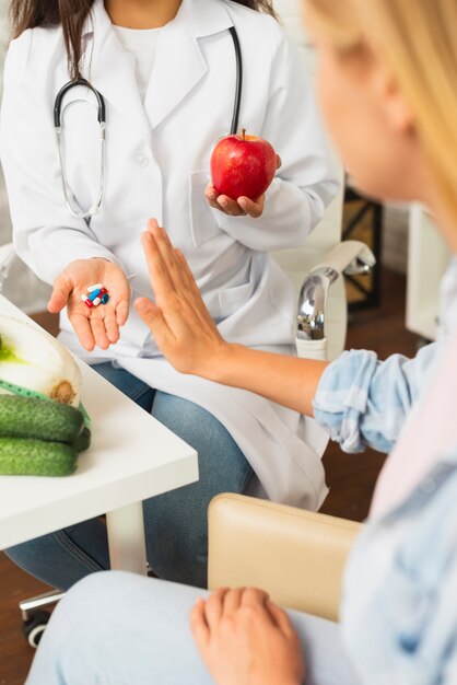 Primer médico comparando frutas con pastillas