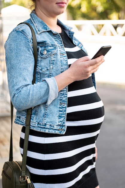 Primer mujer embarazada con smartphone al aire libre