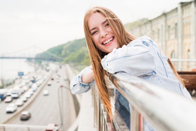 Primer de la mujer joven hermosa feliz que se coloca cerca de la verja