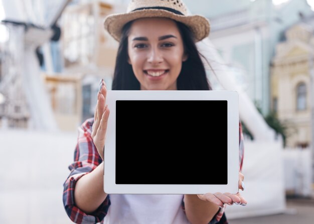 Primer de la mujer joven sonriente que muestra la tableta digital