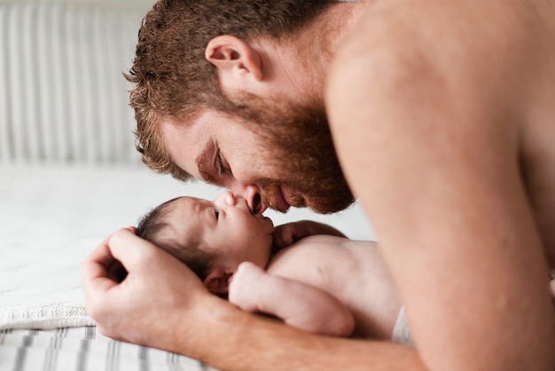 Foto gratuita primer padre con bebé en la cama