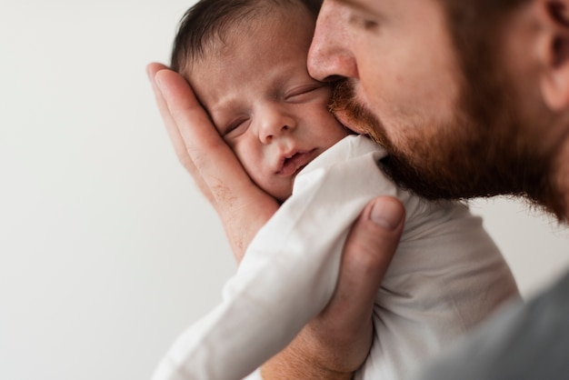 Foto gratuita primer padre besando a su bebé
