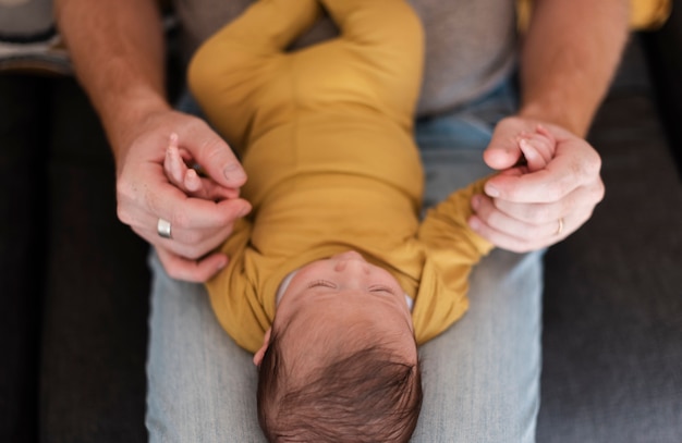 Foto gratuita primer padre sosteniendo al bebé sobre sus piernas