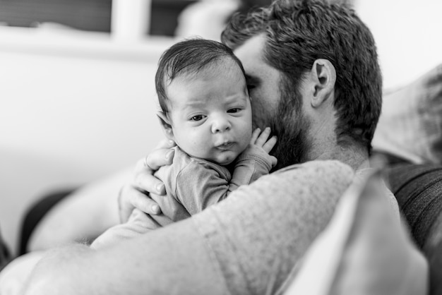 Primer padre sosteniendo bebé en escala de grises