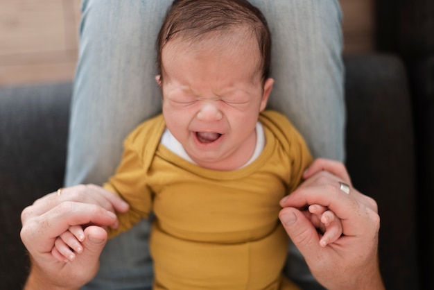 Primer padre sosteniendo bostezo bebé en sus piernas