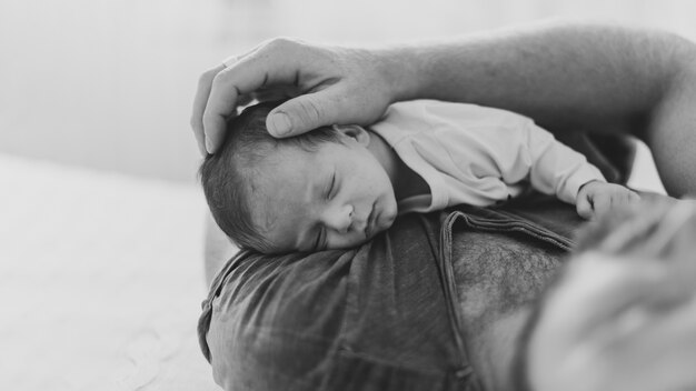 Primer padre sosteniendo sueño bebé en escala de grises