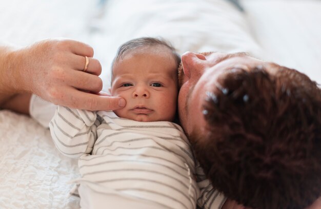 Primer padre tendido en la cama cerca del bebé