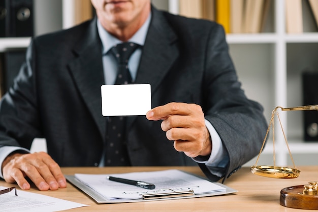 Primer plano del abogado que muestra la tarjeta en blanco blanca con contrato en la mesa