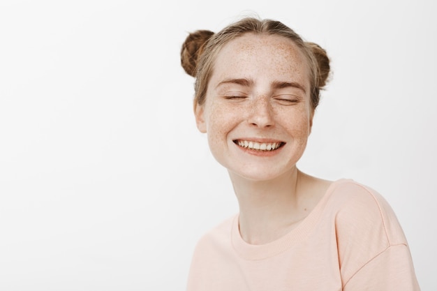 Primer plano de una adolescente feliz soñadora posando contra la pared blanca