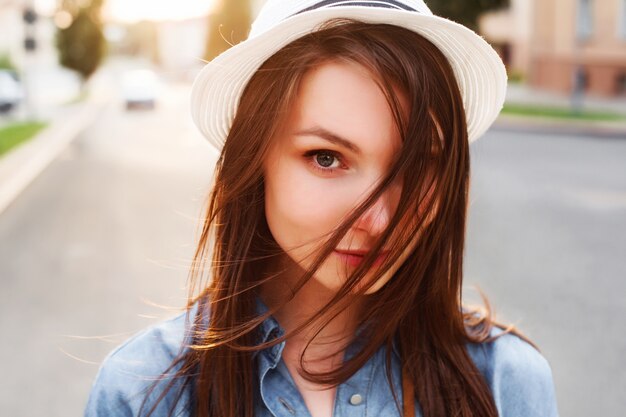 Primer plano de adolescente con sombrero blanco y camisa vaquera