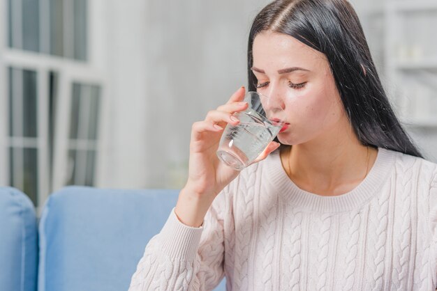 Primer plano de agua potable hermosa joven de vidrio