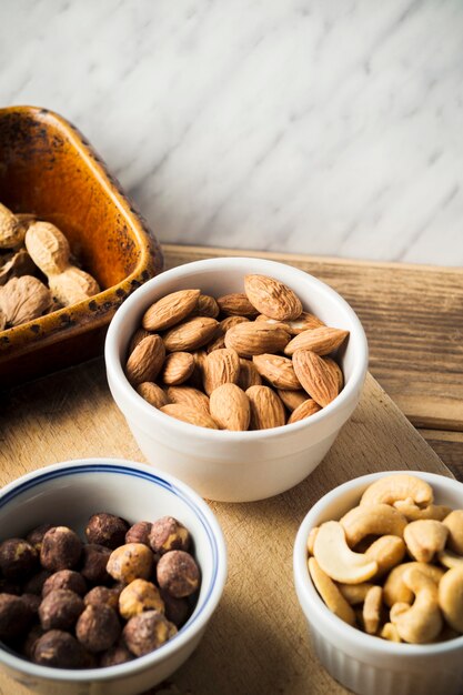 Primer plano de almendra; avellana; Anacardos y cacahuetes en un tazón en una tabla de cortar