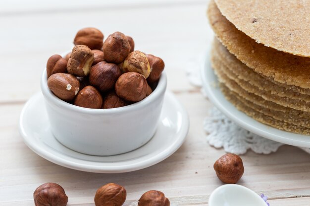 Primer plano de alto ángulo de disparo de avellanas en una taza blanca y panqueques veganos