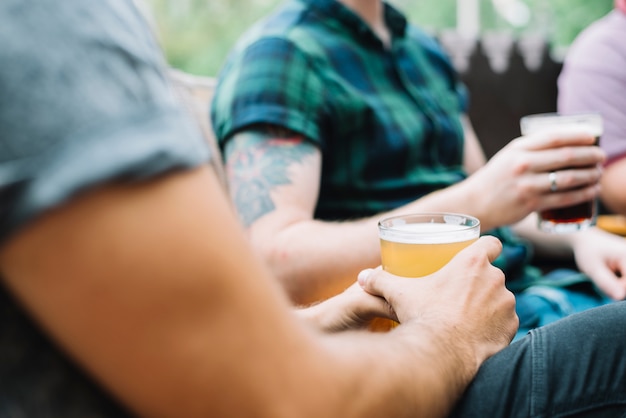 Primer plano de amigos varones con un vaso de bebidas alcohólicas