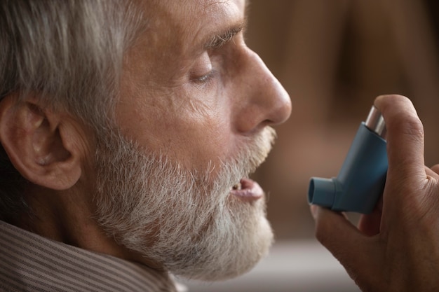 Primer plano anciano sosteniendo inhalador para el asma