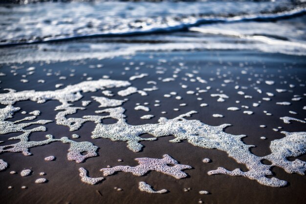 Primer plano de ángulo alto de las espumas del agua del océano