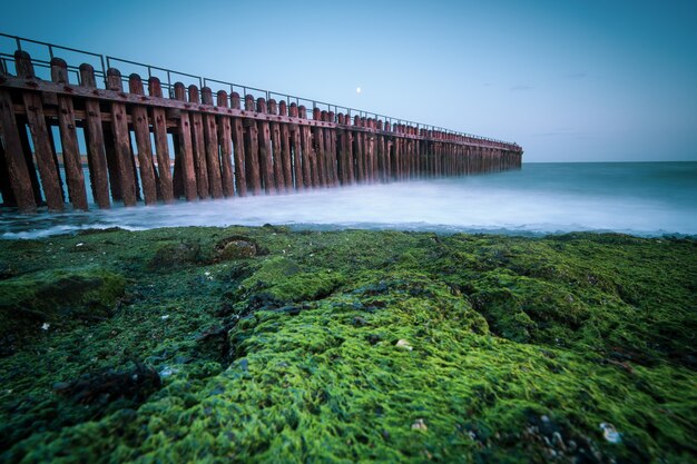 Primer plano de ángulo alto de una valla de madera en la orilla del mar que conduce al mar